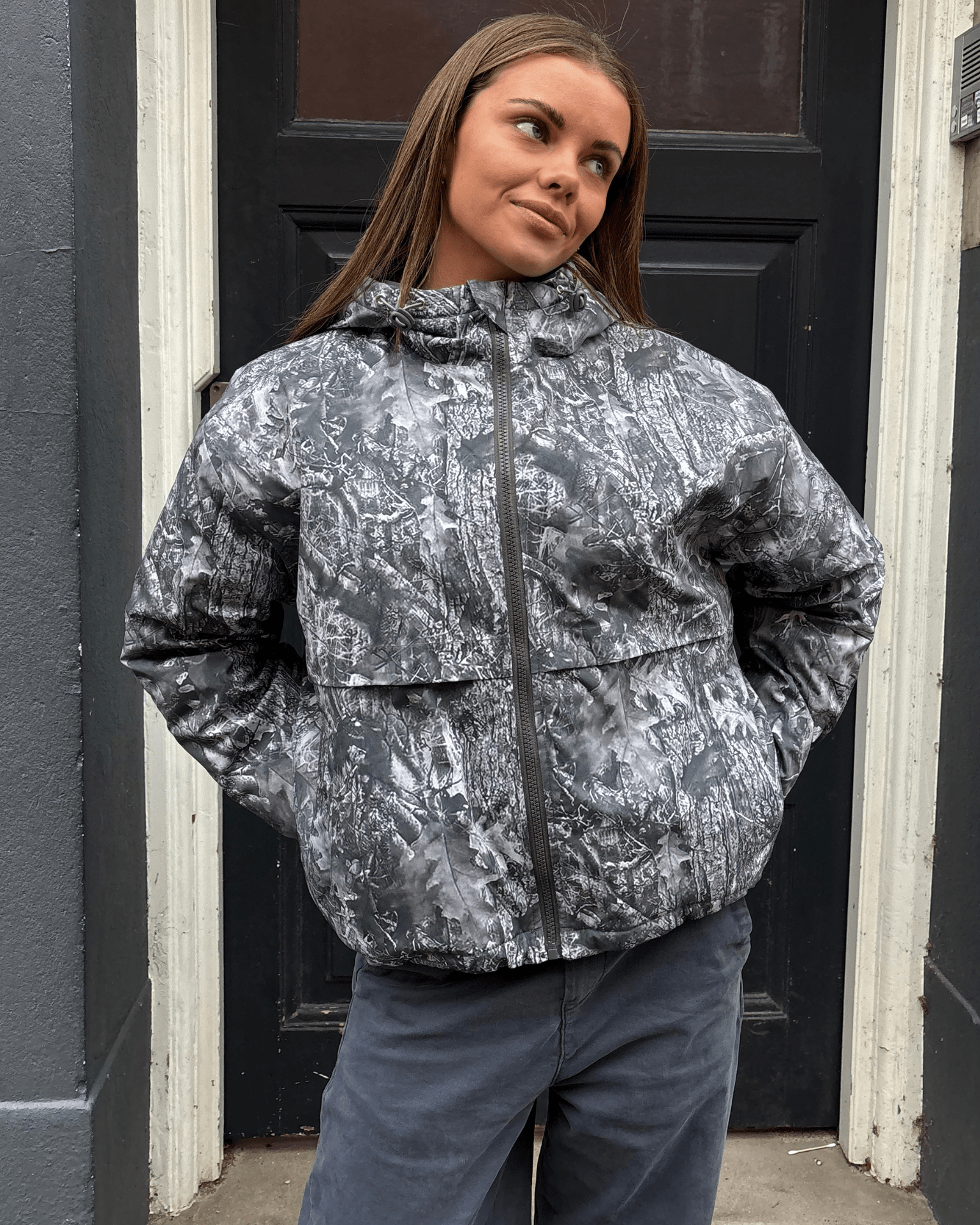 Grå Juno jakke med skov-camouflage, hætte og lynlås på en model