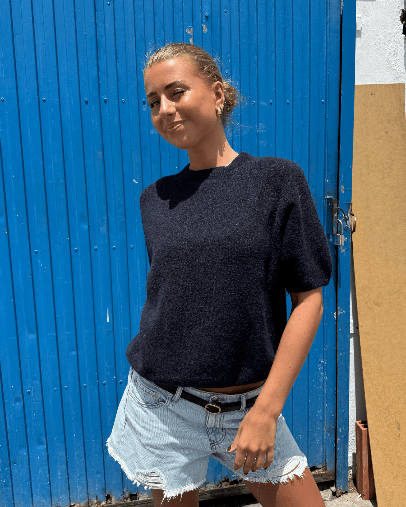 Model i navyblå Mira kortærmet strik med rund hals og lyse denimshorts