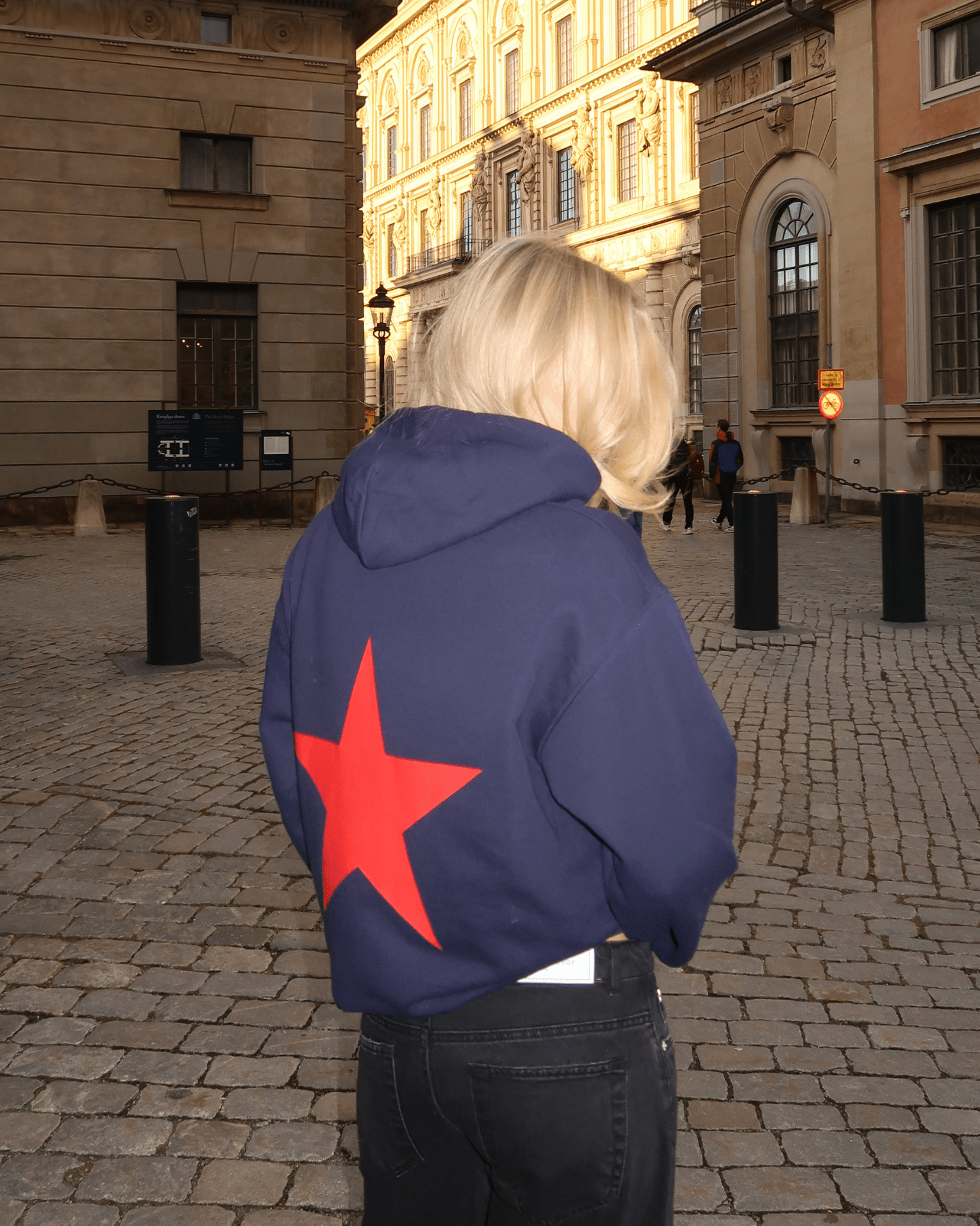 Navy hoodie med stort rødt stjerneprint på ryggen, set bagfra på gaden