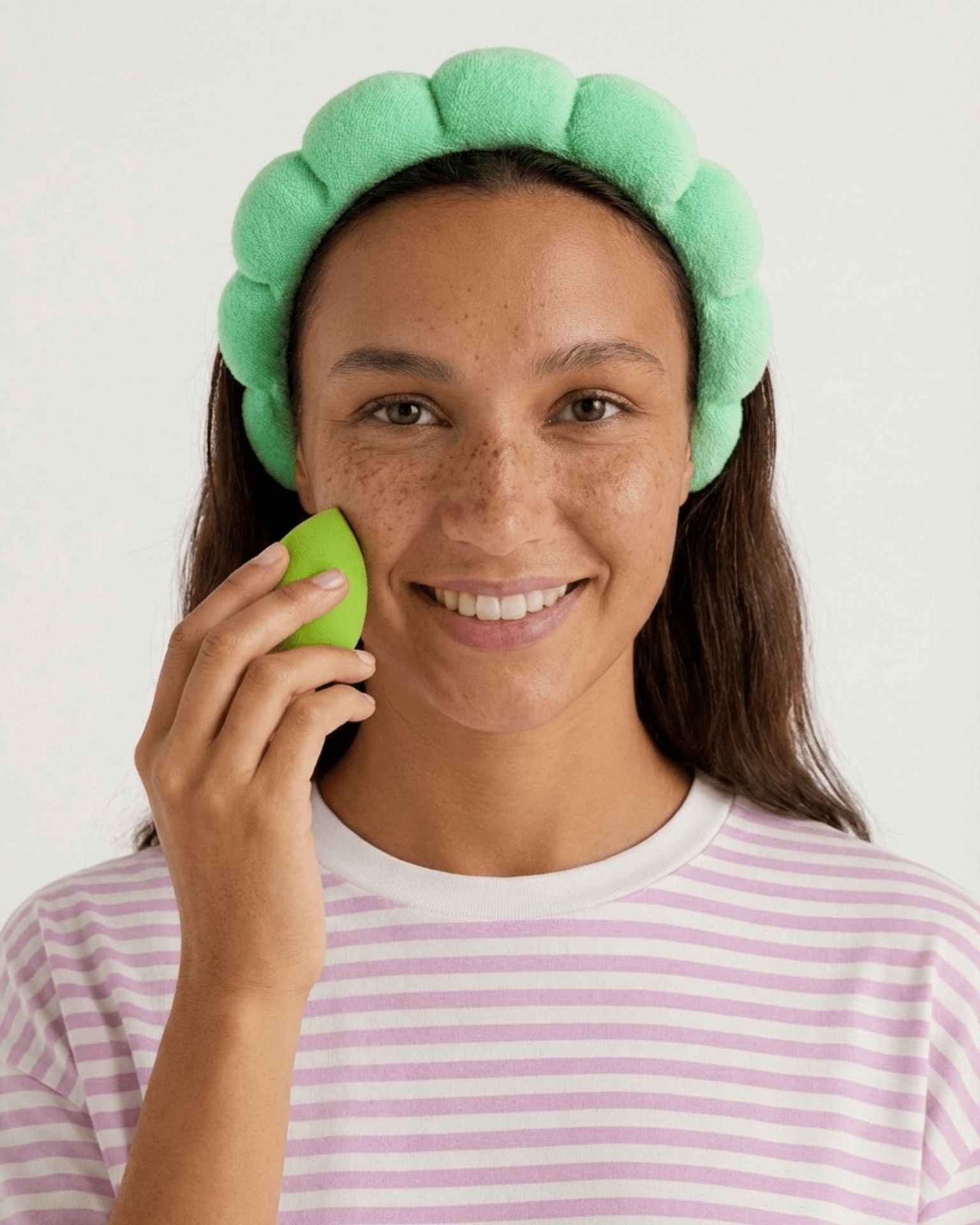 Kvinde med grønt skumpandebånd og grøn beautyblender fra selfcare-sæt