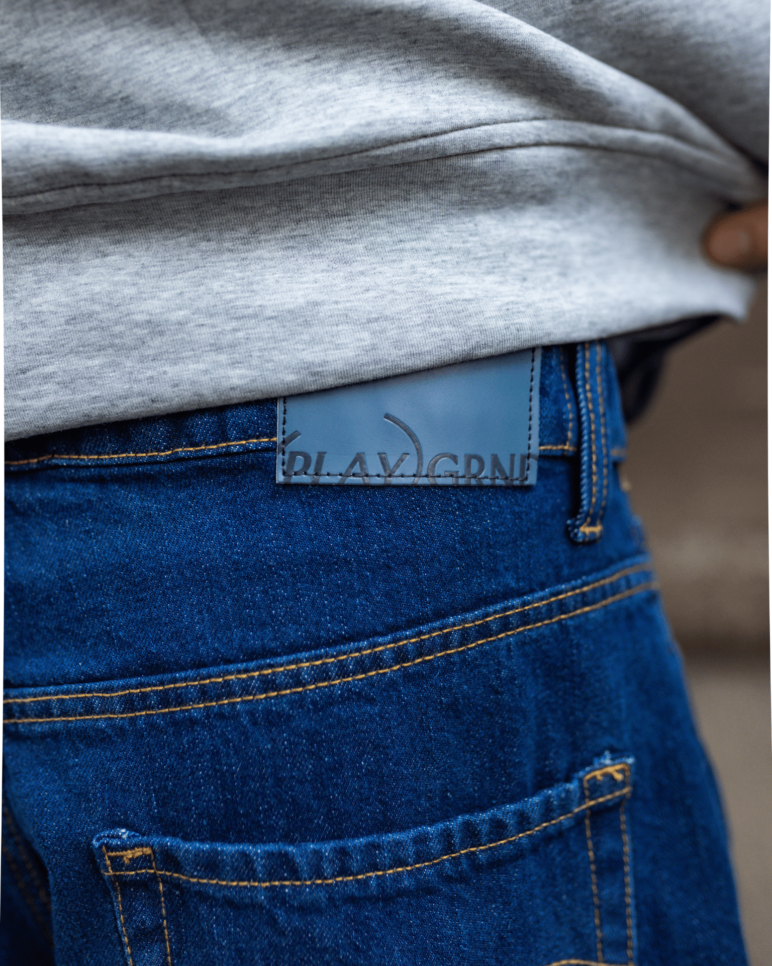 Nærbillede af mørkeblå Tyler baggy jeans med læder mærke bagpå og gule syninger