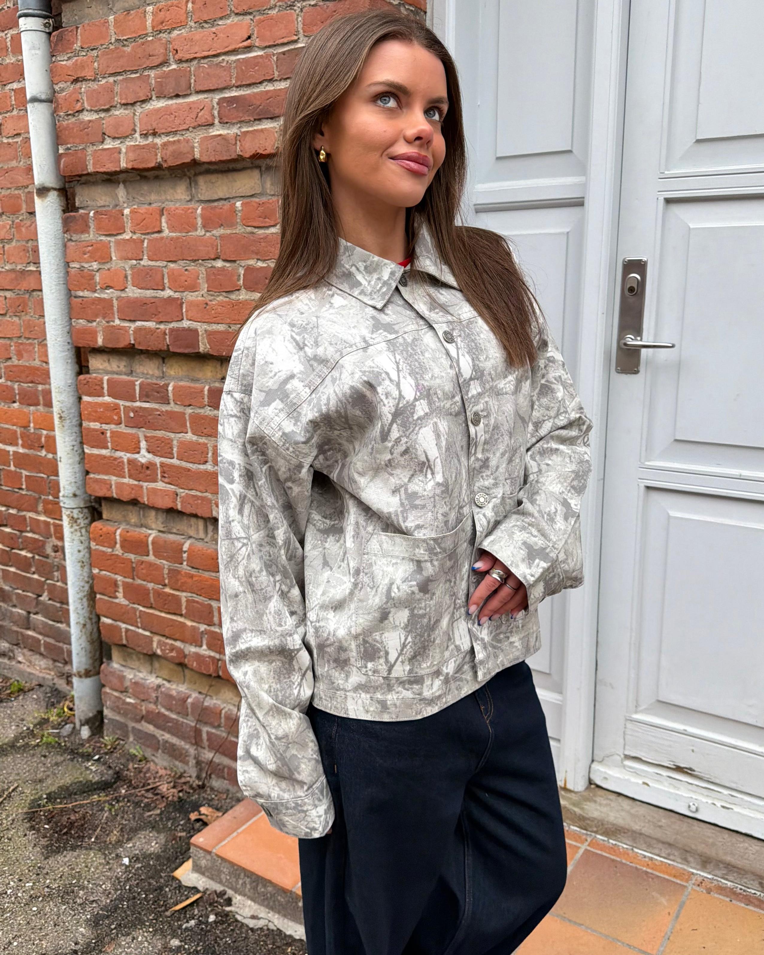 Sia denimjakke i sand forest mønster med knapper og lommer, vist på model