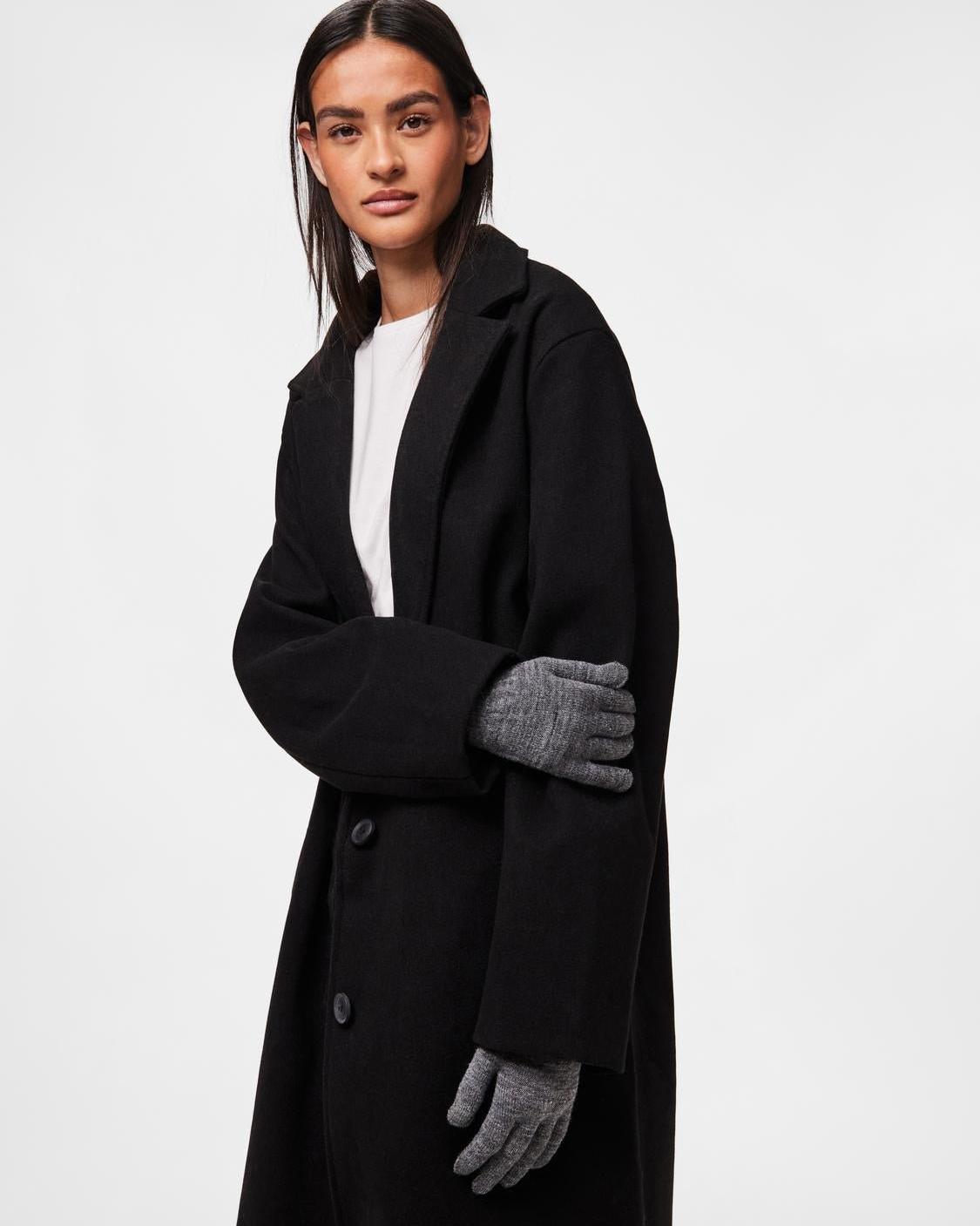Model iført mørkegrå strikkede New Buddy handsker og sort uldfrakke