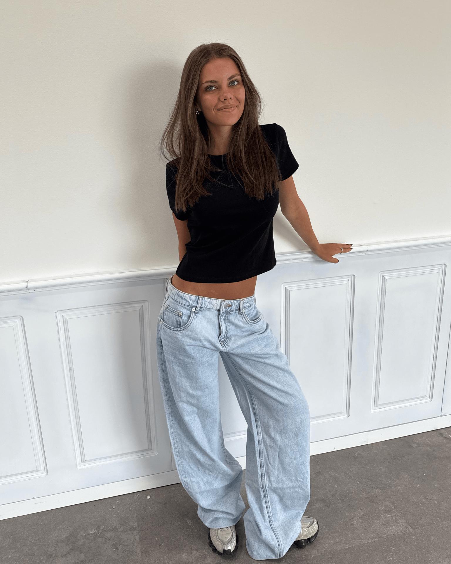 Model i lyseblå Esther jeans med baggy pasform og lav talje samt sort t-shirt