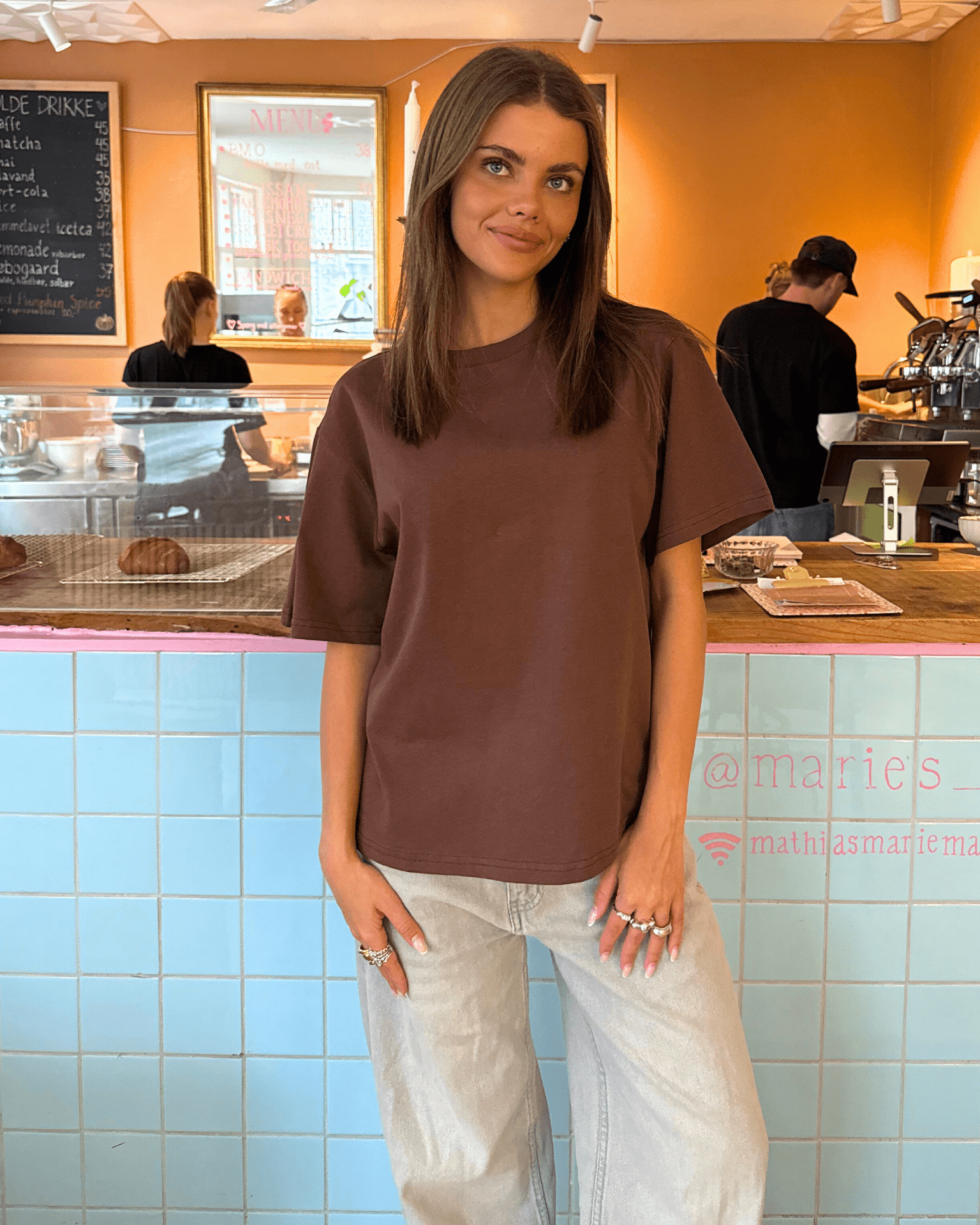 Brun oversize Lykke t-shirt i bomuld og polyester på en model i en café