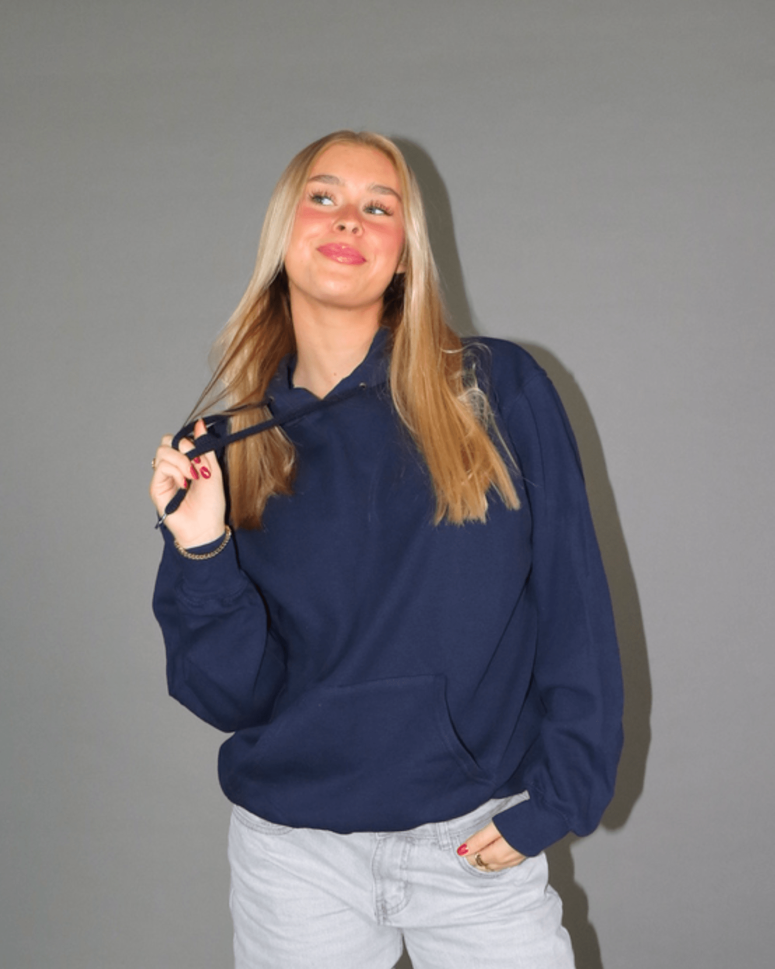 Model i navyblå Red Star hoodie og lyse jeans mod grå baggrund