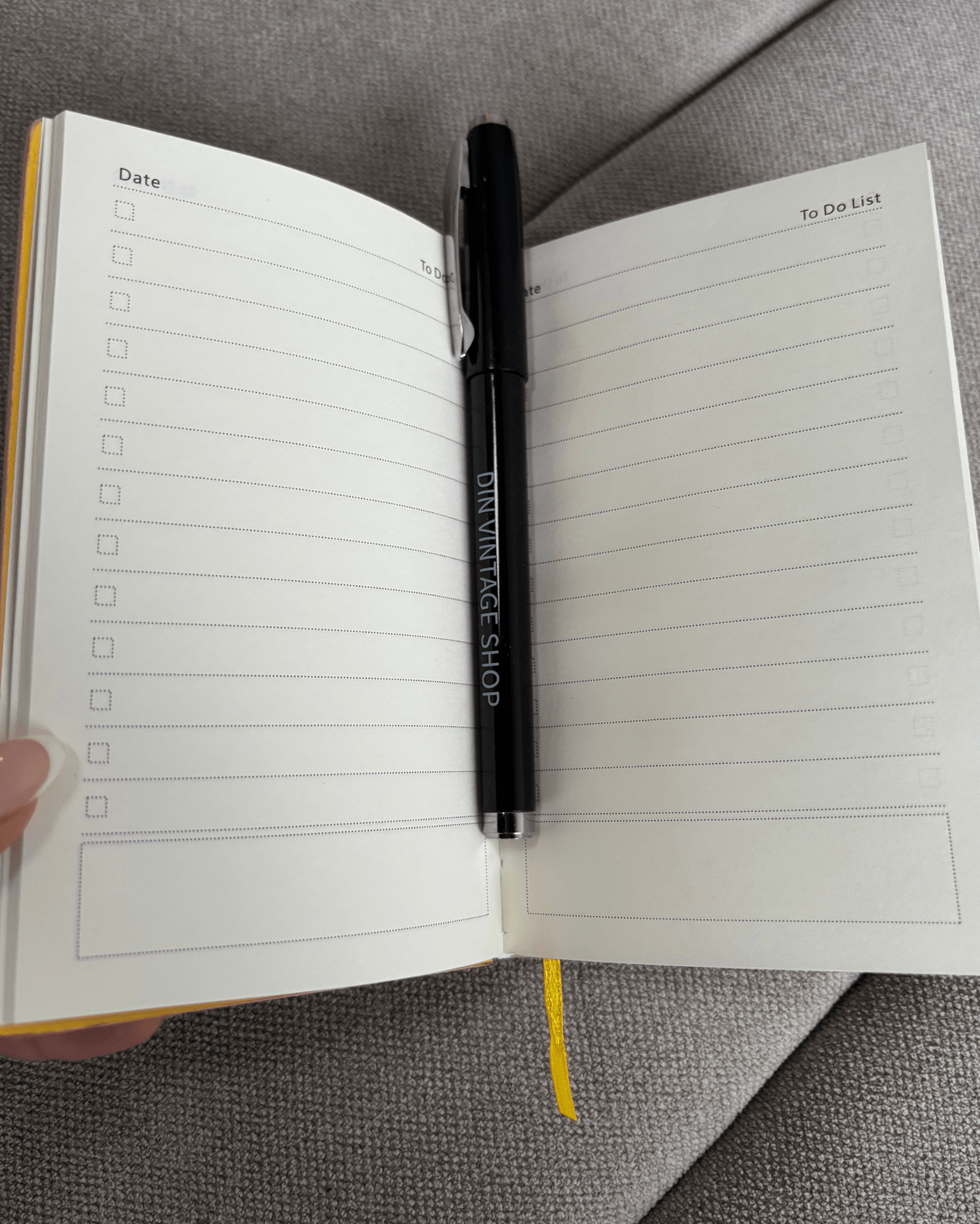 Åben pink planner med to-do lister og en sort Din Vintage Shop kuglepen i midten.