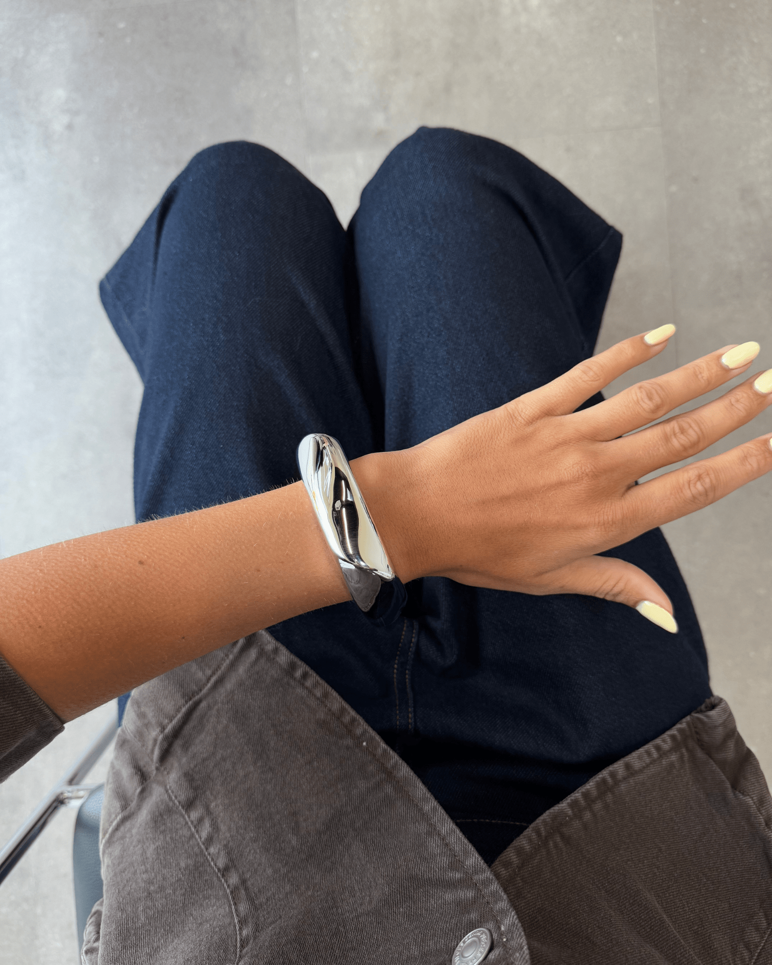 Bredt, sølvfarvet Olena armbånd i organisk design på et håndled