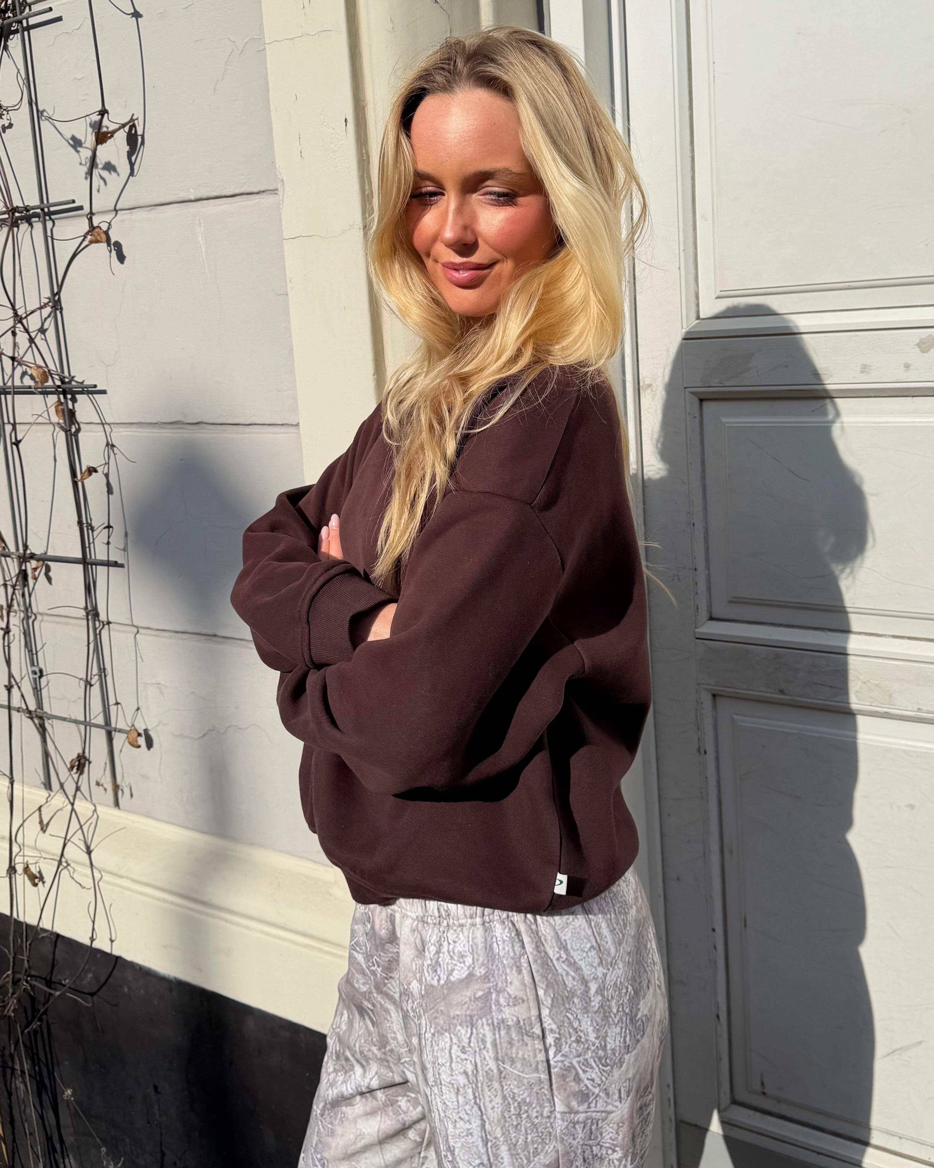 Brun oversized sweatshirt i bomuld på blond model i sollys