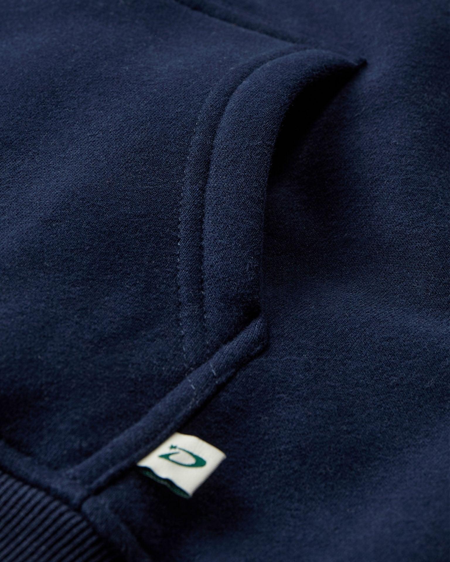 Nærbillede af mørkeblå oversized zip hoodie i blød bomuld med lomme og lille mærke