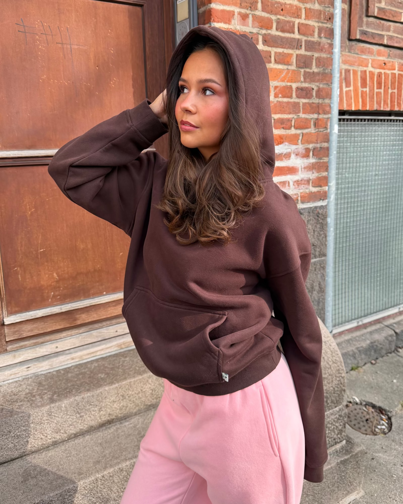 Brun oversized hoodie i blød bomuld med hætte og kængurulomme, vist på en model.