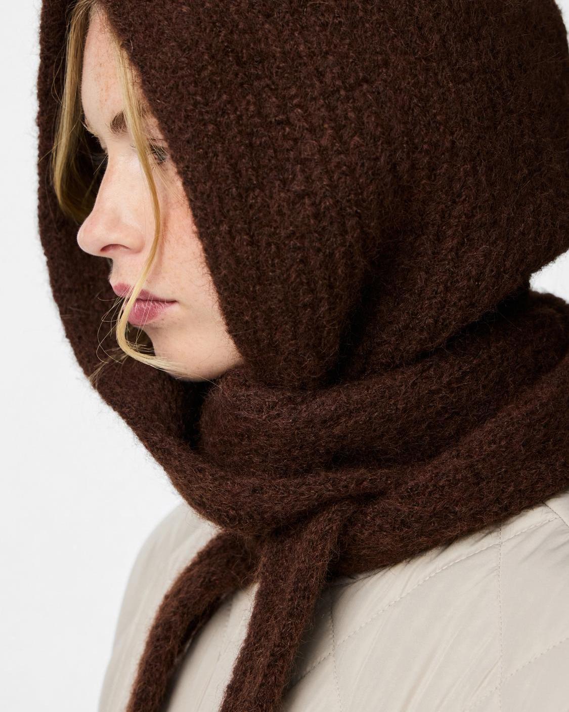 Brun, strikket Rebekka bonnet hue fra PIECES i farven hot fudge, vist i profil på en model.